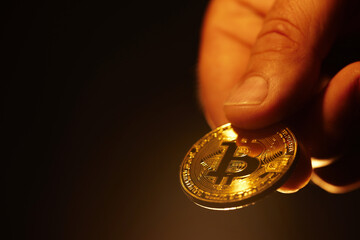 golden bitcoin close-up held in hand on a warm background
