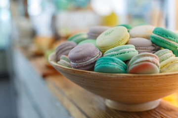 macarons of different colors in a wooden plate on the table