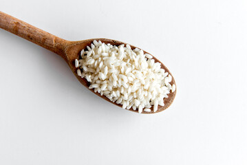 Arborio rice on wooden spoon, risotto rice on white background top view.
