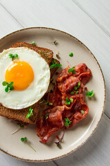 Breakfast, fried egg with bacon, micro-green, on a light background, no people, selective focus,