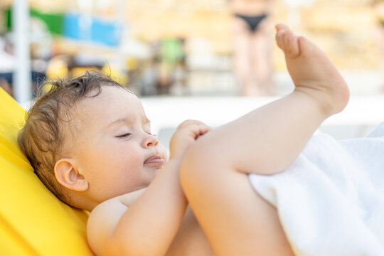 Toddler Is Relaxing Sitting On Plastic Folding Lounge Beach Chair With Yellow Color Mattress.baby Is Playing With Mommy Sunglasses Or Putting White Blanket In Mouth.vacation With Kids Concept.