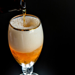 filling beer glass on black background.