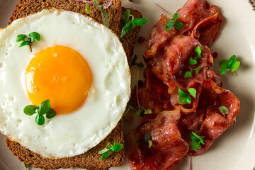 Breakfast, fried egg with bacon, micro-green, on a light background, no people, selective focus,