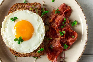 Breakfast, fried egg with bacon, micro-green, on a light background, no people, selective focus,