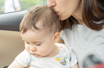 mother kissing baby top of the head.love,care,warm and secure.maternity,motherhood concept.toddler in mom's arms in a car.vacation with kids,family trip.