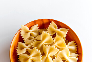 raw tie pasta in wooden pot and white background (farfalle pasta).