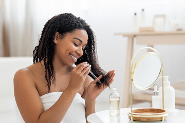 Happy Black Lady Applying Moisturising Oil On Damaged Hair Ends After Shower