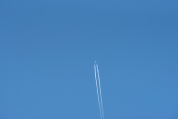 Jet airplane with contrails across a cloudless blue sky