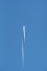 Jet airplane with contrails across a cloudless blue sky