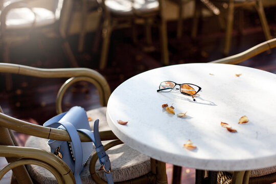 Autumn cafe outdoors. Eyeglasses and fallen leaves on table