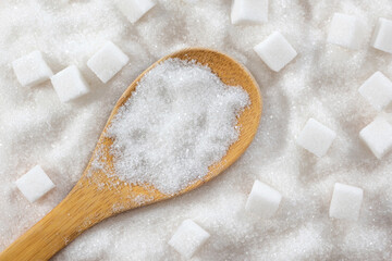 Sugar in a wooden spoon on a white sugar background