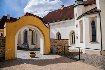 Fototapeta na wymiar Litomysl, Czech Republic, 17 April 2022: gothic medieval church of the Exaltation of the Holy Cross with tower at sunny summer day, Chapel of St. Marquette, stone statues