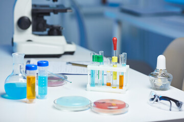 Laboratory interior: test tubes, petri dishes, protective eyewear, dropper and papers on desk