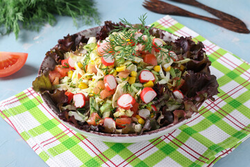Cabbage salad with crab sticks, tomatoes and corn served on lettuce leaves © Anzhela