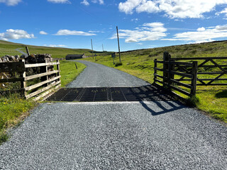Cattle grid, high on the moors, with a farm building, and sunny weather near, Malham, Skipton, UK