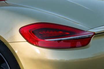 The golden car. Advertising concept. Car headlight close-up. Beautiful background. Rear side view.