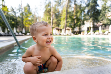 Little cute adorable blond playful beautiful caucasian active toodler boy enjoy playing at pool...