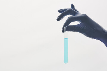 Close-up of unrecognizable chemist in protective gloves analyzing chemical sample while holding test tube against white background