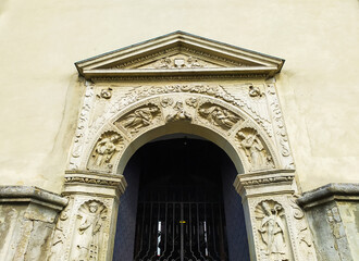 Fototapeta premium Zhovkva, Ukraine. The entrance to the St. Lawrence Church. Ancient aged carved gates. Ornate arched portal to the temple. Renaissance archivolt with niches with figures of evangelists.