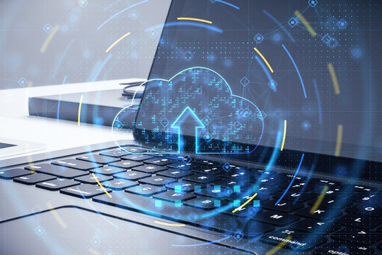 Cloud computing technology and data storage concept with digital graphic glowing blue cloud symbol with arrow up on laptop background, double exposure