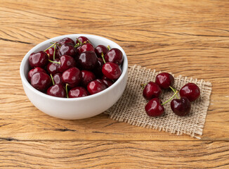 Red cherries on a bowl over wooden table