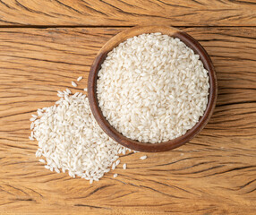 Raw carnaroli risotto rice in a bowl over wooden table