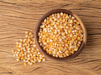 Dried corn or popcorn grains in a bowl over wooden table