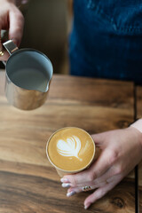 The process of making a barista cappuccino with a beautiful pattern in the form of a heart on the...