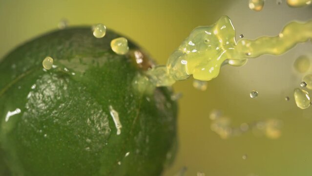 Fresh Lime fruit squirting with juice in slow motion in green nature background 4K
