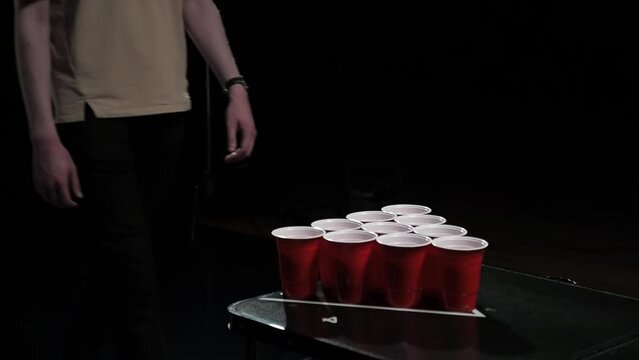 Close-up of players with red plastic beer cups. Playing beer pong at the party on dark background. 
