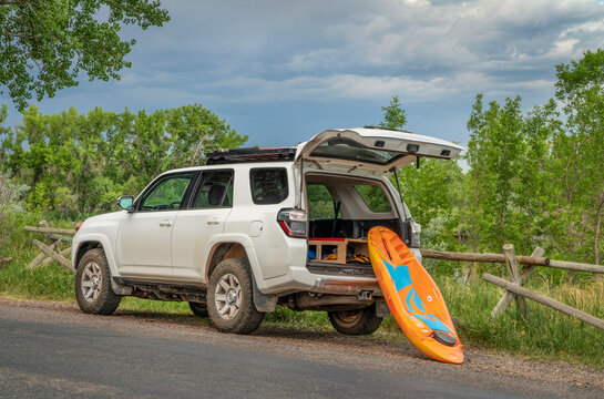 Fort Collins, CO, USA - June 27, 2022 : A prone kayak by Bellyak is being loaded into Toyota 4Runner SUV on a lake shore  after paddling session.