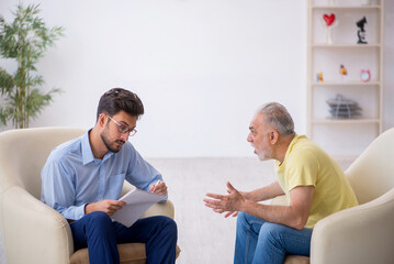 Obraz premium Old man visiting young male psychotherapist