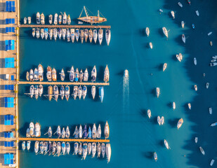 Aerial view of boats and luxure yachts in dock at sunset in summer in Pula, Croatia. Colorful landscape with sailboats and motorboats in sea bay, jatty, clear blue sea. Top view of harbor. Travel