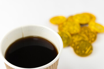 紙コップのコーヒーと、オモチャの金貨。ラテマネーのイメージ