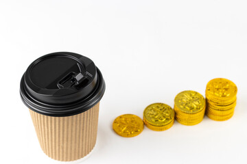 紙コップのコーヒーと、オモチャの金貨。ラテマネーのイメージ