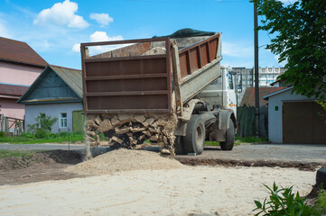 Dump trucks carrying good filling a field, giving rise to a fine soil. Preparation and construction.