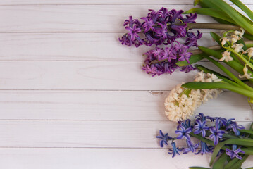 Top view on bright spring hyacinth flowers lay on white wooden table background. Flatly copy space for text. Selective focus