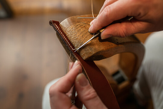Handmade. the girl sews a leather belt in the workshop. Wooden machine. Atmospheric photo. Close up