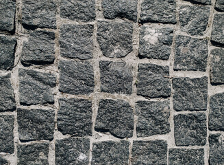 Texture of dark gray granite paving stones, top view. Background from natural block stone.