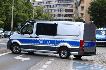 Radiowóz polskiej policji jedzie alarmowo ulicami miasta. 