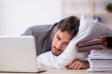 Young male employee in oversleeping concept