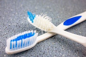An old used toothbrush and a new one. Close-up of a used toothbrush and an unused one.