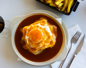 Hearty Portuguese lunch Francesinha, sandwich with bread, ham, fresh sausage, roasted meat, melted...