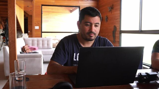 a man working remotely in a country house with his laptop and annoyed and disappointed looking at the screen with his friend in the daytime in 4k
