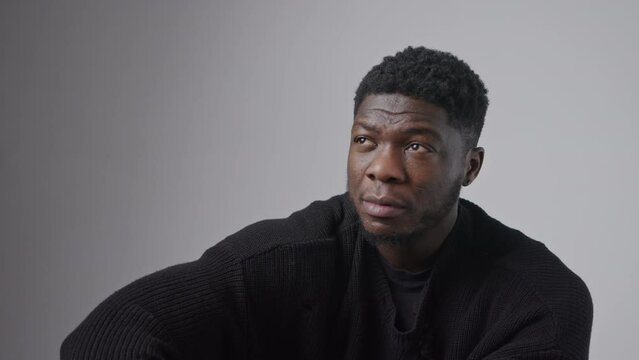 Handsome Afro American man moves his eyes to the camera medium closeup grey background studio shot copy space . High quality 4k footage