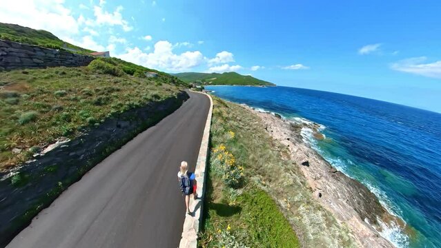 Top view of a tourist woman on the cliff of Pietracorbara beach close to Erbalunga town in Corsica island of France. Aerial view of the coast in Mediterranean sea.