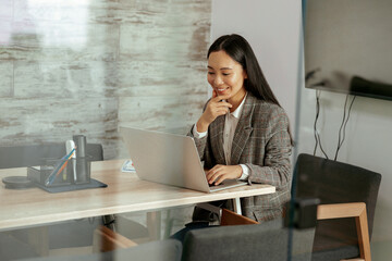 Smiling asian woman working laptop sitting in meeting room in office. High quality photo