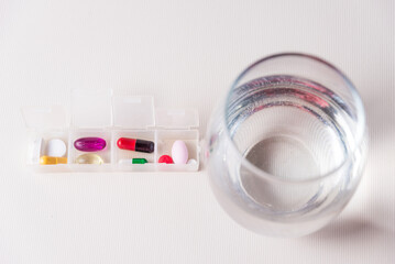 pills sorted in a pillbox with a glass of water, medicinal, pandemic, health and wellness concept