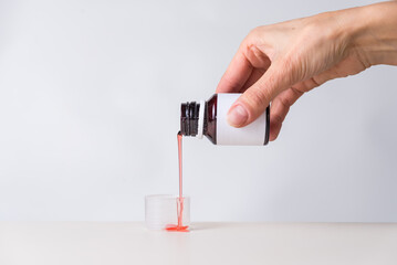 pink syrup dropping into a measuring cap, cough, copy space, health and wellness concept