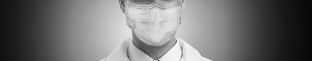 Closeup view of man wearing medical face mask on grey background, banner design. Black and white photography